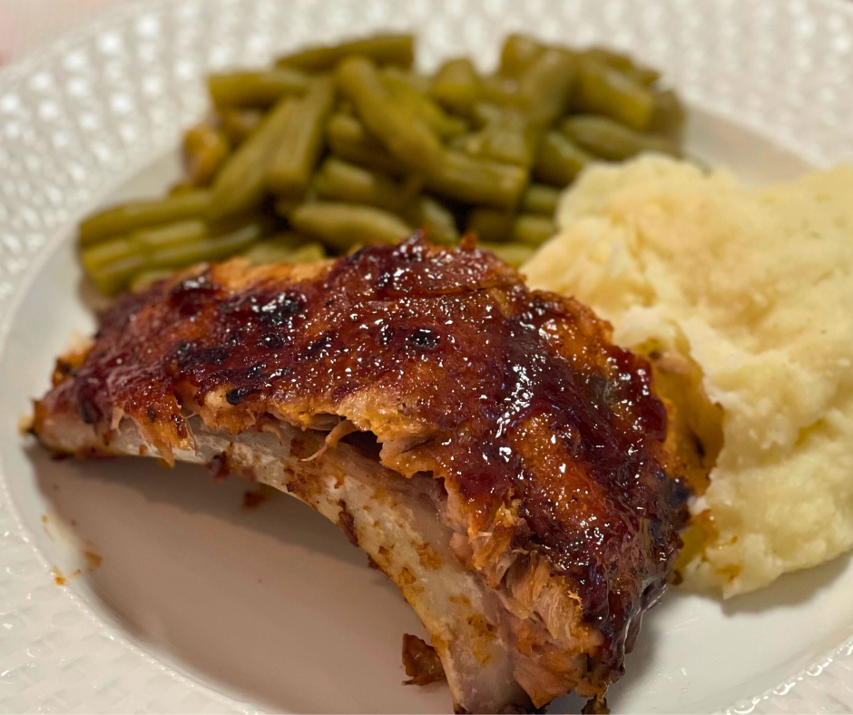 BBQ ribs on a plate with mashed potatoes and green beans