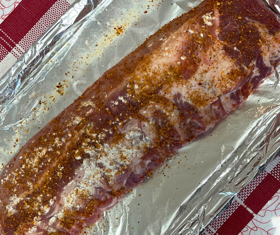 a rack of ribs on a baking sheet covered with foil and coated with seasoning ready to bake