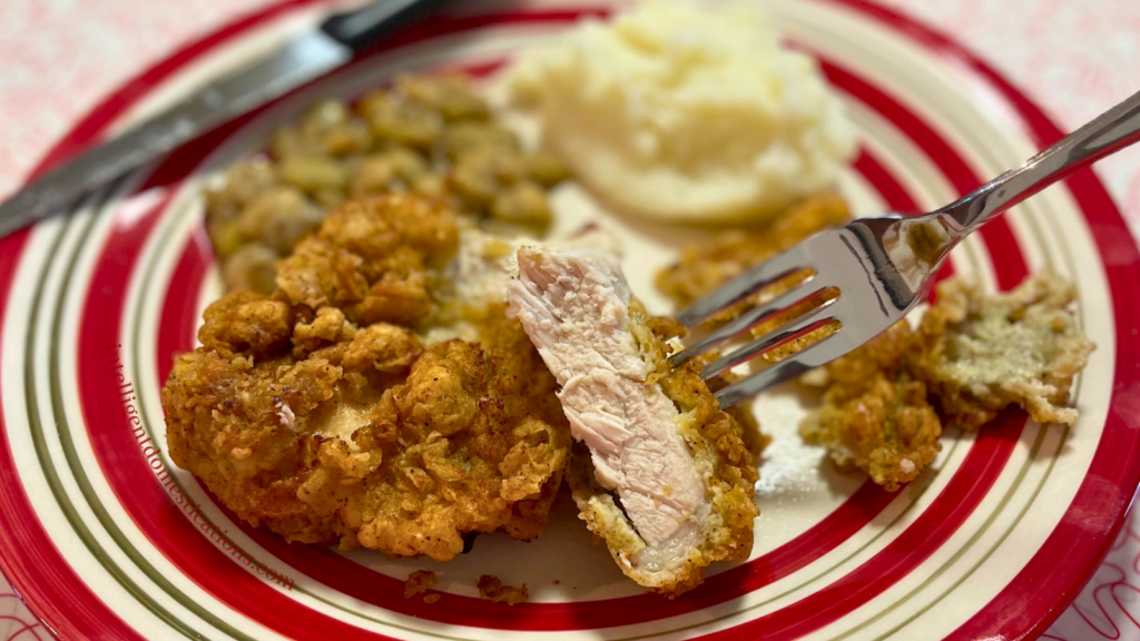 Fried pork chops with lima beans and mashed potatoes on a red and white dinner plate