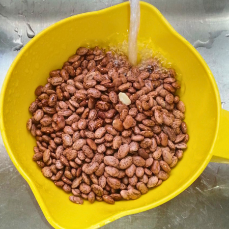 Rinsing dried Pinto beans in a colander