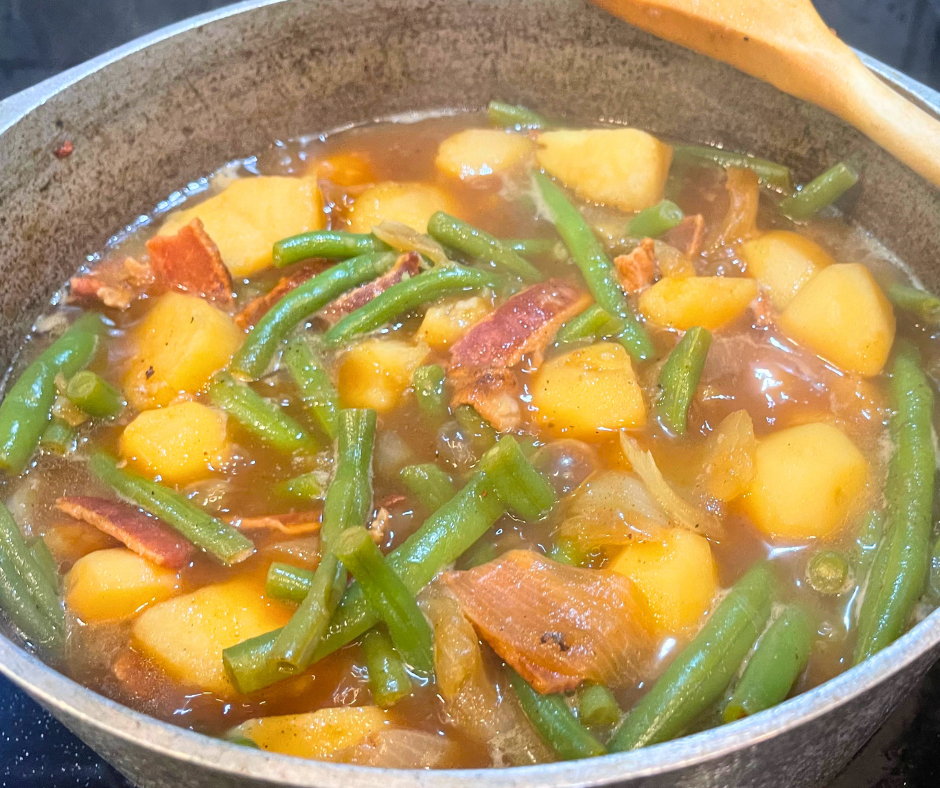 Green beans with potatoes bacon and onions simmering in a pot